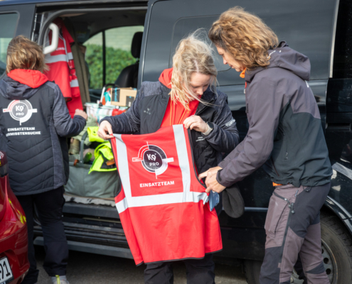 Ein Mann holt eine Warnweste aus dem Kofferraum eines Autos.