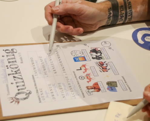 Eine Hand hält einen Stift und schreibt auf eine Tafel.