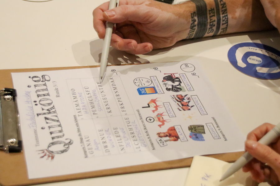 Eine Hand hält einen Stift und schreibt auf eine Tafel.