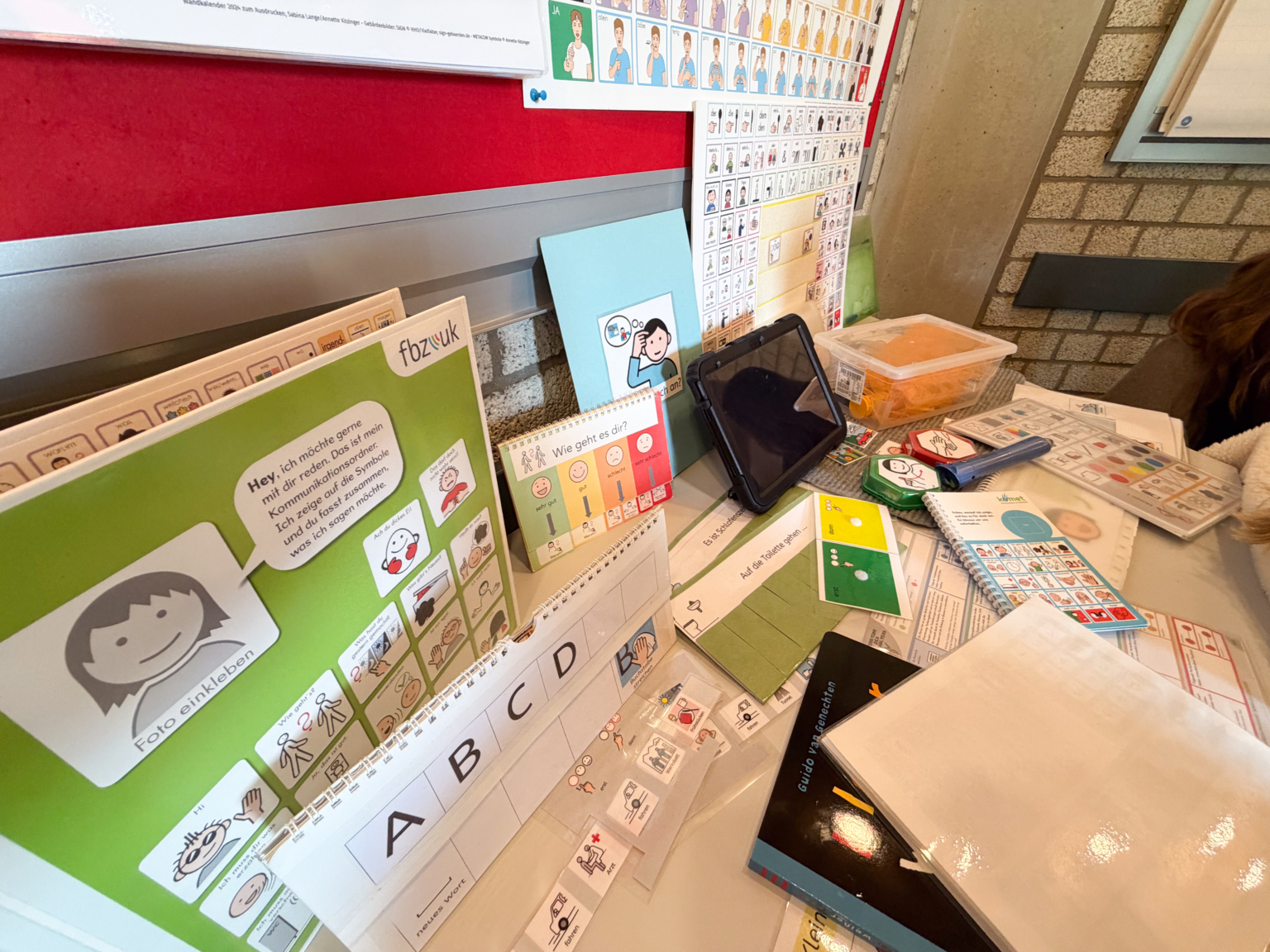 Ein Kind sitzt vor einem Tisch. Auf dem Tisch liegen Karten und ein Tablet.