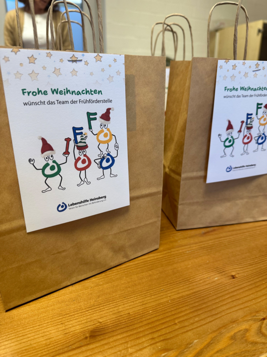 Weihnachtsgeschenke in roten Papiertüten. Es liegen ein paar Geschenke auf einem Tisch.