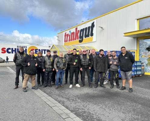 Eine Gruppe von Leuten in schwarzer Kleidung steht vor einem Laden. Sie lächeln und schauen in die Kamera.