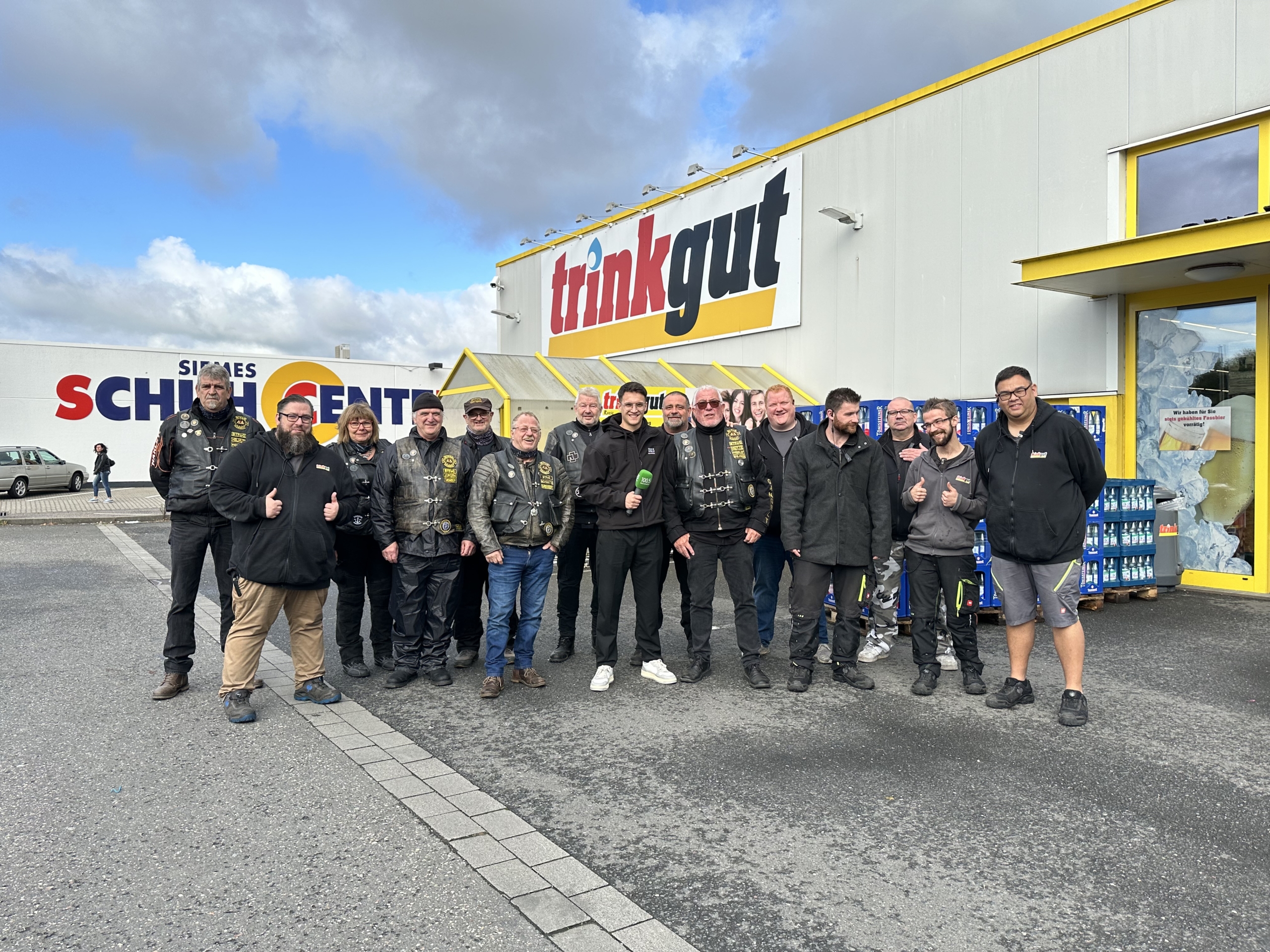 Eine Gruppe von Leuten in schwarzer Kleidung steht vor einem Laden. Sie lächeln und schauen in die Kamera.