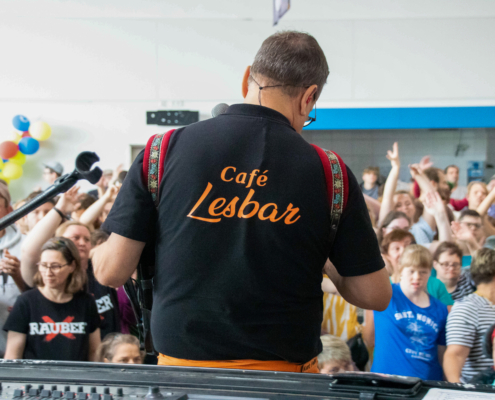 Ein Mann singt vor einer Menge Menschen. Er steht auf einer Bühne und hat ein Mikrofon in der Hand.