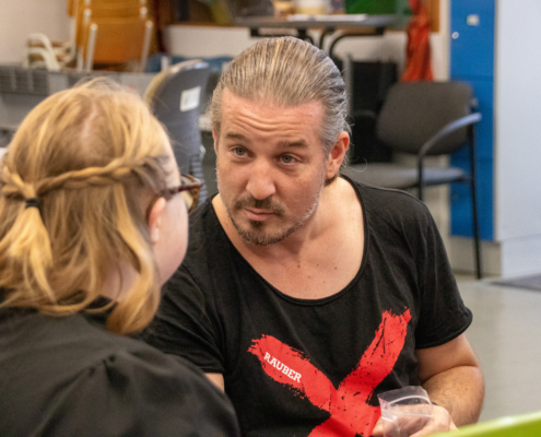Ein Mann mit Bart schaut nach oben. Er trägt ein rotes T-Shirt.