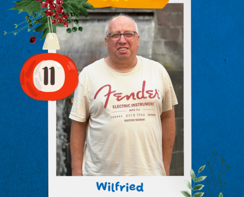 Ein Mann mit Brille lächelt. Er trägt ein weißes T-Shirt.