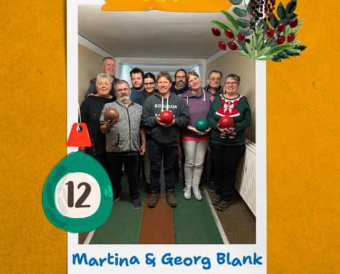 Eine Gruppe Menschen steht in einem Raum. Einige tragen Karnevalskostüme und halten bunte Bälle.