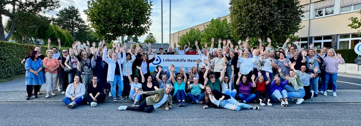 Viele Menschen stehen vor einem Gebäude und winken.