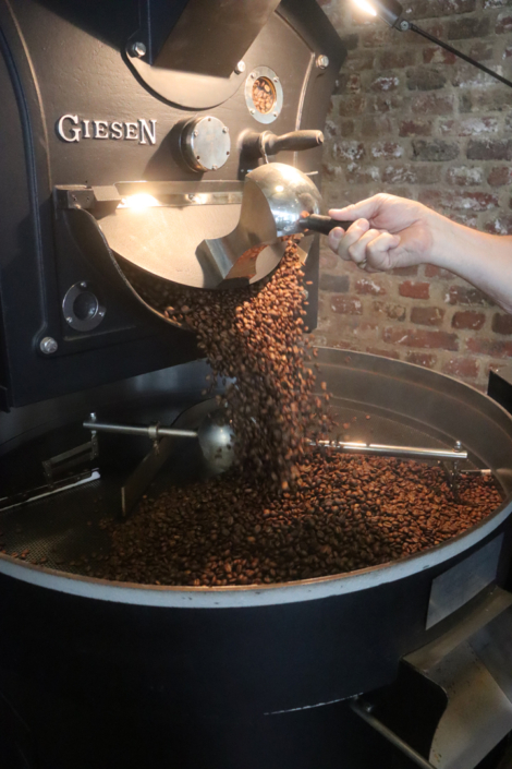 Kaffee wird aus einer Maschine. Es sieht aus wie braune Bohnen.