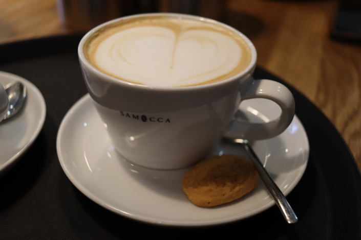 Eine Tasse Kaffee mit einem Keks auf einem Teller.