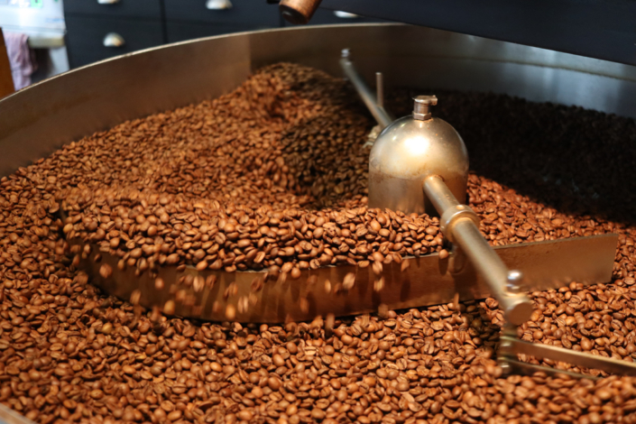 Kaffee-Bohnen in einer großen Maschine. Sie werden bewegt.