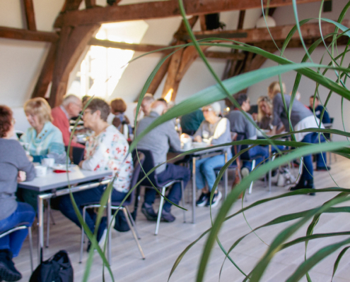 Menschen sitzen an Tischen. Sie essen und trinken. Es sieht aus wie ein Treffen oder eine Veranstaltung.