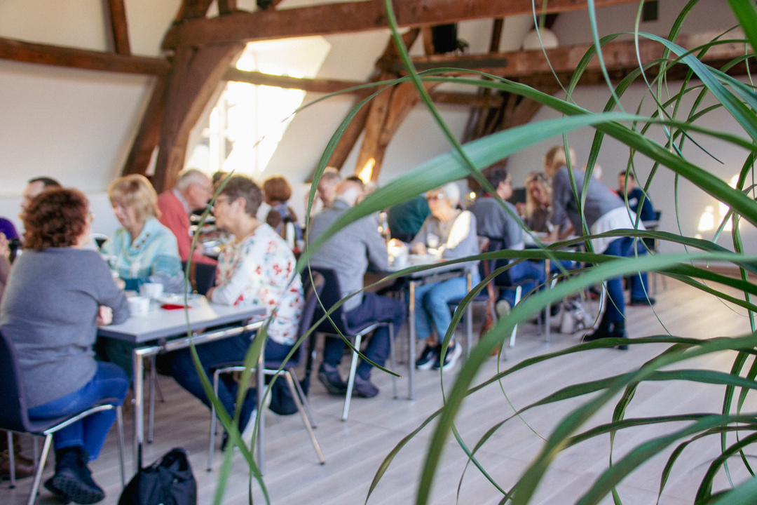Menschen sitzen an Tischen. Sie essen und trinken. Es sieht aus wie ein Treffen oder eine Veranstaltung.