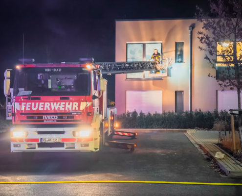 Feuerwehr fährt rückwärts aus einer Einfahrt. Es ist dunkel und die Lichter der Feuerwehr sind an.