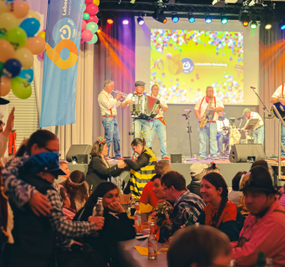 Eine Band spielt auf einer Bühne. Es sitzen viele Menschen davor.