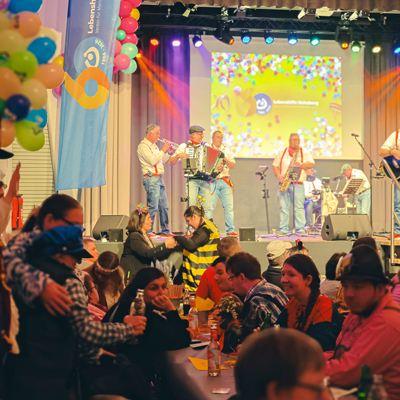 Eine Band spielt auf einer Bühne. Es sitzen viele Menschen davor.